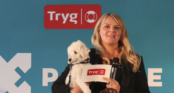 Kathrine Bjerga Tøraasen introduserer startupen Tracy -- som har laget en fitbit for hund -- mens hun holder en av brukerne deres på armen. Foto: Tryg Xplore Kathrine Bjerga Tøraasen introduserer startupen Tracy -- som har laget en fitbit for hund -- mens hun holder en av brukerne deres på armen. Foto: Tryg Xplore