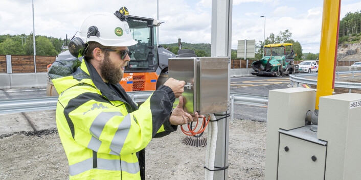 Med logo på vernehjelmen sto gründerne bak Distruptive Engineering ute på anlegget til nye E18 og installerte sensoren sin. dagen før åpning. Foto: Distruptive Engineering Med logo på vernehjelmen sto gründerne bak Distruptive Engineering ute på anlegget til nye E18 og installerte sensoren sin. dagen før åpning. Foto: Distruptive Engineering