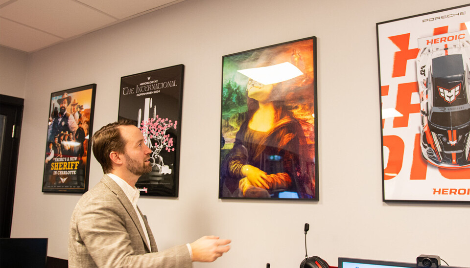 Harg viser frem flere av Heroics fargerige events-plakater. Harg foran flere av Heroics fargerige events-plakater.