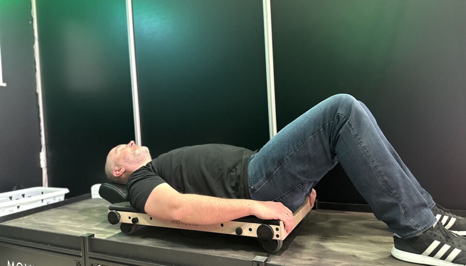 Christopher Scheiene i Movelio demonstrerer hvordan man bruker massasjeapparatet. Ved å sparke fra med beina skyver han seg frem og tilbake, rammen er på hjul - og under ligger en rulle.