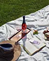 Piknik med alkoholfri vin, bok, og frukt på et teppe.