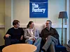 Tre personer fra TheFactory sitter i sofa på Oslo-kontor foran blått TheFactory-skilt.
