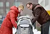 Ungt par går tur med sitt lille barn i barnevogn. Familie. Kjernefamilie. Harmoni. Lykke. Rød kåpe. A couple is going for a walk with the pram. Foto: Frank May / NTB NB! MODELLKLARERT